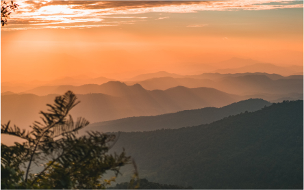 foggy mountains with sun setting behind them